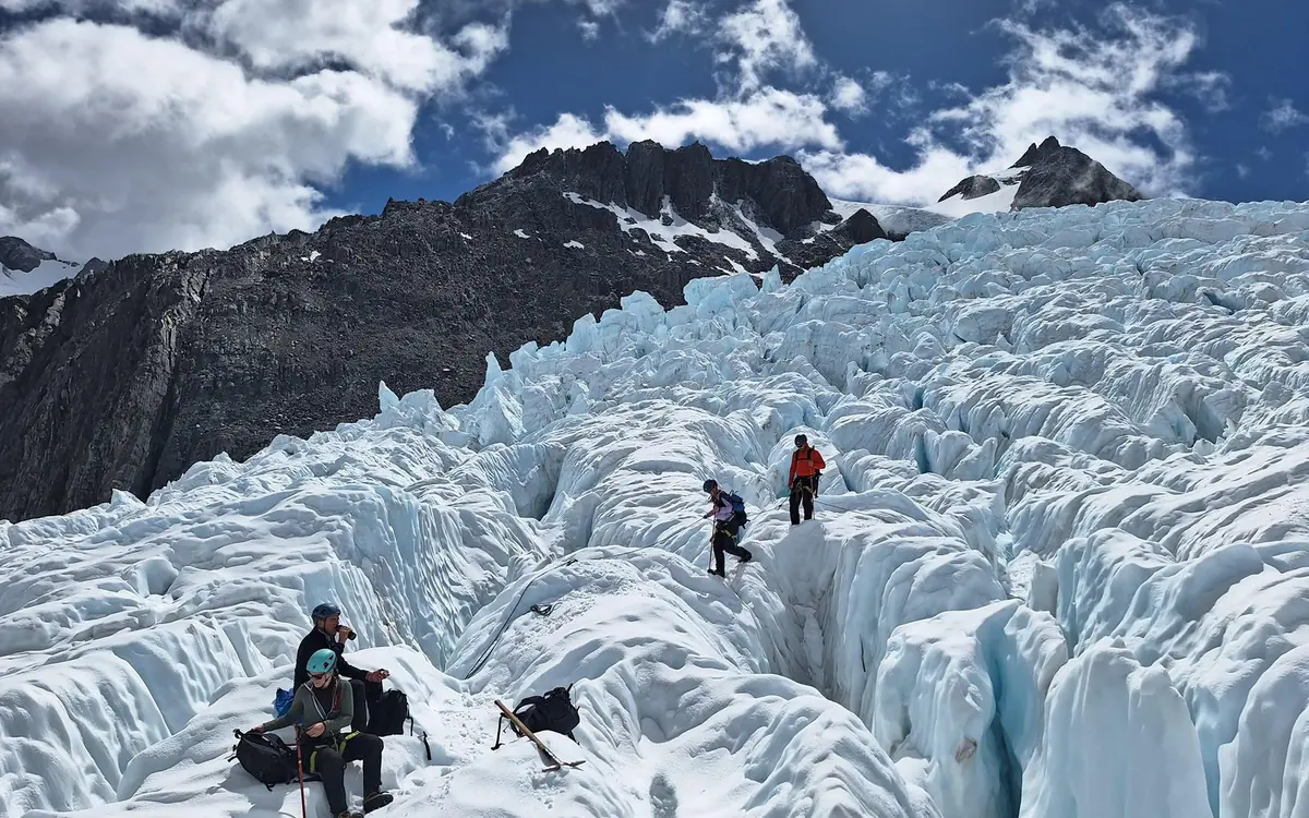 A line of hikers in crampons crossing the ice on Franz Josef Glacier