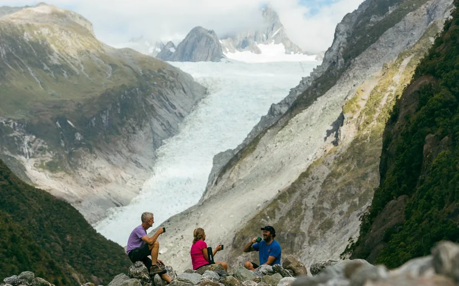 A small group sitting above the Fox Glacier valley with the ice behind