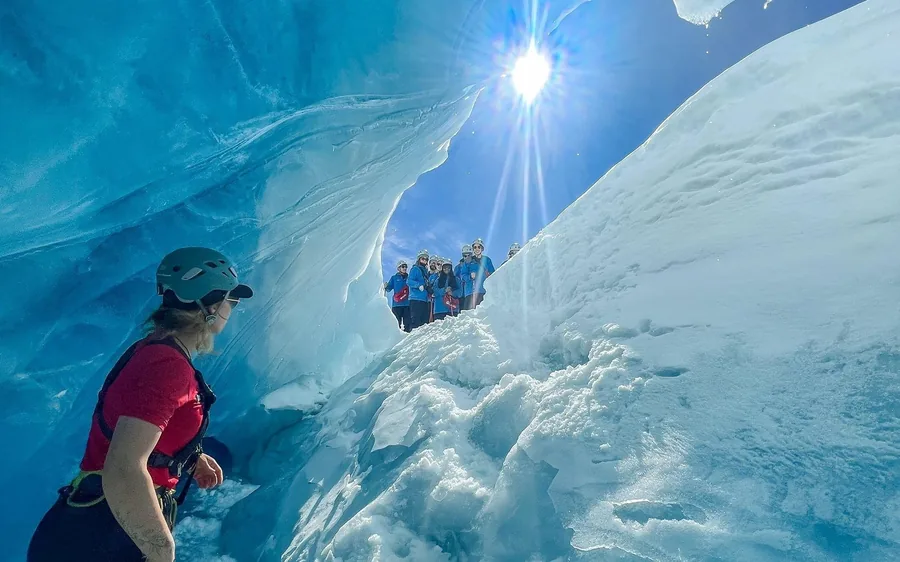 A hiker inside a blue ice tunnel high on Franz Josef Glacier