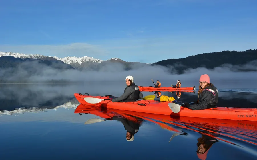 A red sea kayak on the still surface of Lake Mapourika at dawn