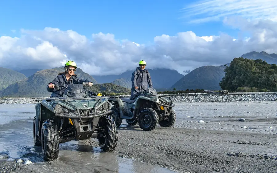 Two quad bikes on the braided riverbed with the Southern Alps behind